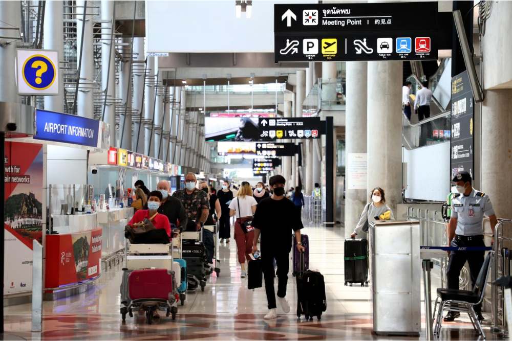 Touristes avec bagages dans un aéroport thaïlandais